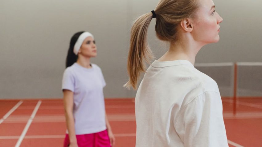 Two women engaged in a badminton match on an indoor court, highlighting active sportswear.